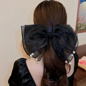 Detailed back view of a black organza bow hair clip with pearls on a model hair
