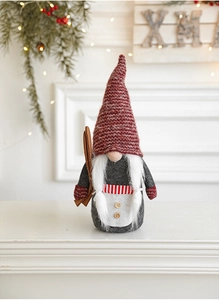 Gnome de Noël en peluche avec bonnet rouge et skis sur une cheminée blanche décorative
