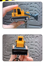 Close-up of a mini yellow alloy bulldozer keychain with movable shovel detail