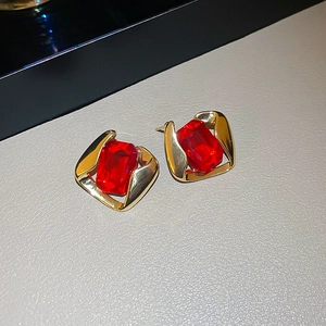 Detail of vintage gold stud earrings with large faceted red faux gemstones on leather