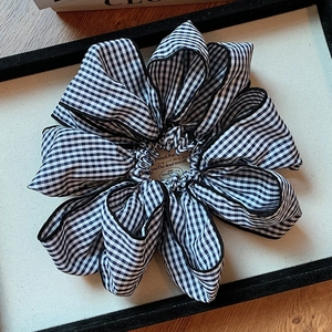 Classic black and white gingham scrunchie with lace edge in a minimalist wood display