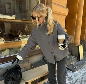 Détail d'un manteau gris en laine avec col montant et boutons noirs en scène européenne