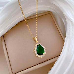 Detail of gold titanium necklace with teardrop green emerald and zircon halo setting