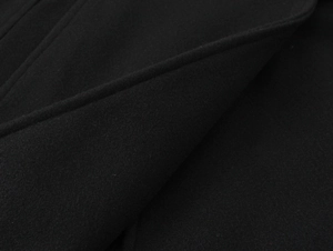 Close-up of black wool-blend fabric texture and fine stitching on a cropped coat collar