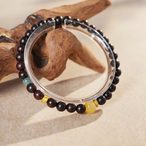 Detail of sandalwood bracelet featuring translucent green and yellow beads with gold spacers