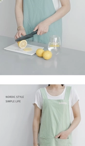 Detail of mint green linen kitchen apron with wide straps and a front storage pocket