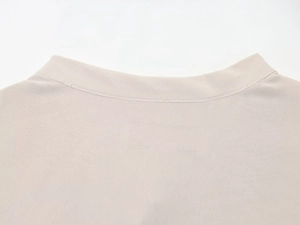 Detail of high-quality stitching on the beige shirt neckline with soft fabric texture