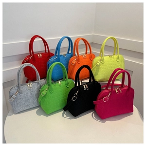 Detailed view of colorful felt shell bags with crocodile texture and gold hardware