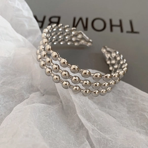 Macro shot of three-layer silver bead open bracelet with polished metallic finish
