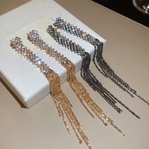 Detail view of rhinestone tassel earrings in gold and gunmetal finish on white box