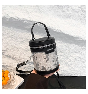 Detail of black leather and white lace embroidery bucket bag with elegant metal hardware