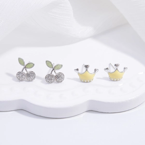 S925 sterling silver cherry and crown stud earrings set on a white ceramic plate