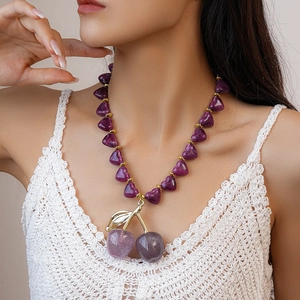 Detail of purple acrylic heart bead necklace with sparkly cherry pendant on model