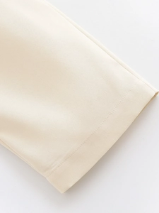 Detailed close-up of high-waisted trousers featuring beige twill fabric and premium stitching