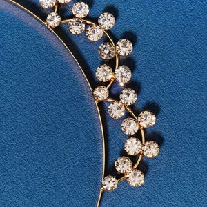 Elegant gold metal headband with sparkling crystals on dark background