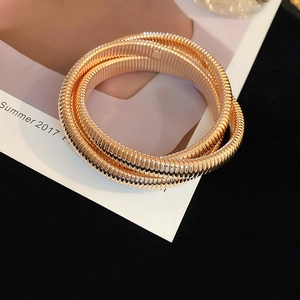 Detail of gold multi-layer elastic bangle with fine spring texture on dark background