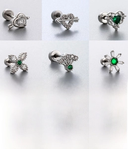 Detailed close-up of surgical steel screw studs with green zircon and heart designs