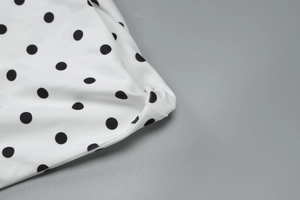 Detail shot of white fabric with black polka dots showing stitching and textile texture