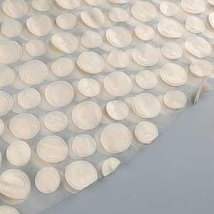 Close-up of elegant floral 3D applique on ivory mesh dress fabric with satin details