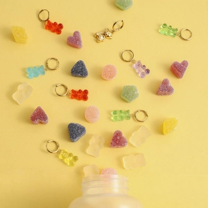 Boucles d'oreilles oursons colorés en acier inoxydable et résine sur fond jaune vif