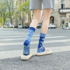 Detail of blue asymmetric crew socks with floral and bunny patterns worn with sandals