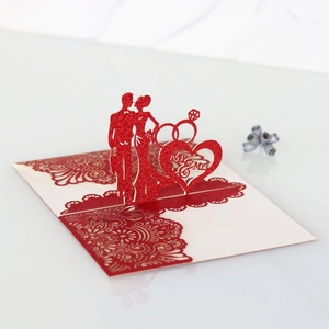 Close-up of laser-cut 3D pop-up wedding card featuring Mr & Mrs heart and red rose patterns
