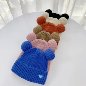 Detailed close-up of colorful knit beanies with bear ears and heart embroidery patterns
