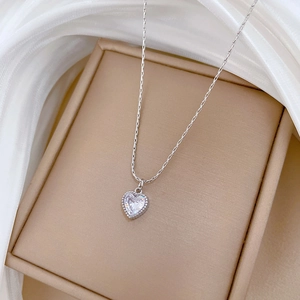 Detail of silver heart pendant with transparent gemstone on elegant silk background