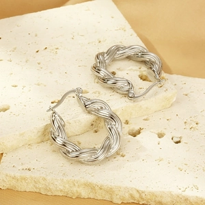 French vintage twisted hoop earrings in silver stainless steel on a beige travertine stone