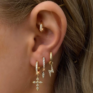 Macro shot of gold hoop earrings with sparkling cross and lightning bolt zircon charms
