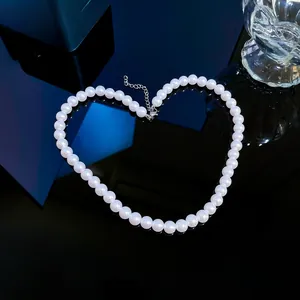 Elegant white pearl necklace arranged in a heart shape on black reflective surface