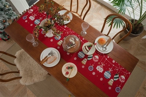 Detailed view of a red Christmas table runner with festive bells and snowflake patterns