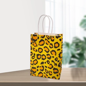 Sac cadeau vertical en papier kraft léopard avec poignées en corde blanche sur bois
