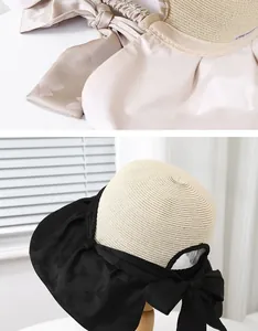 Detail of elegant straw sun hat with large bow and fine texture on a wooden stand