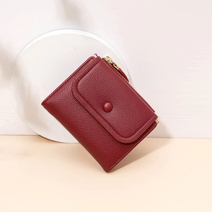 Macro detail of wine red wallet with lychee pattern texture and snap button closure
