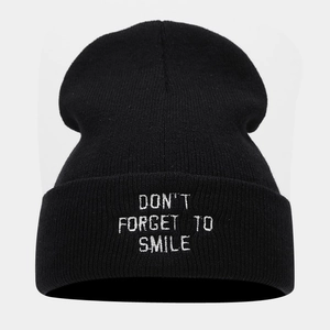 Detail of white 'DON'T FORGET TO SMILE' embroidery on black knitted beanie cuff