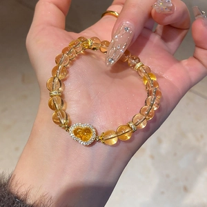 Close-up of citrine beaded bracelet with zircon Wu Lou charm on a female hand