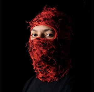 Detail of red and black distressed knit balaclava showing frayed texture and street style