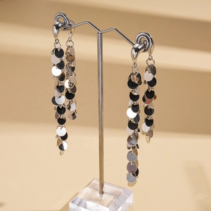 Détail de boucles d'oreilles pendantes à paillettes argentées sur présentoir métal
