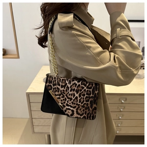 Detail showing leopard print and black panel stitching with gold chain on a fashion handbag