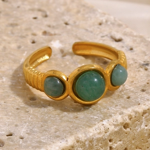 Macro shot of 18K gold plated ring with three green aventurine stones on a stone base