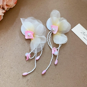 Detail of long fringe earrings featuring white chiffon flowers and pearly bead tassels