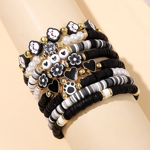 Detail of layered polymer clay bracelets featuring heart and flower charms on a model wrist