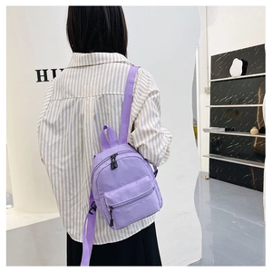Detail of a purple nylon mini backpack with adjustable straps worn by a model