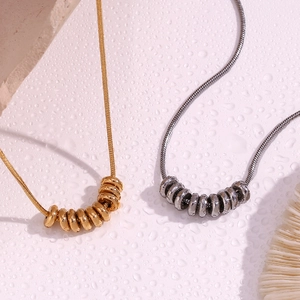 Detail of 18K gold and silver plated bean pendants on sleek snake chains with water drops