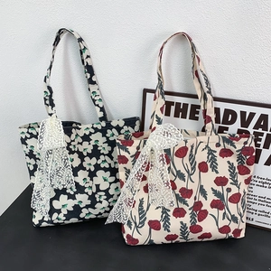 Detail of canvas tote bags in black and beige with floral patterns and lace bows