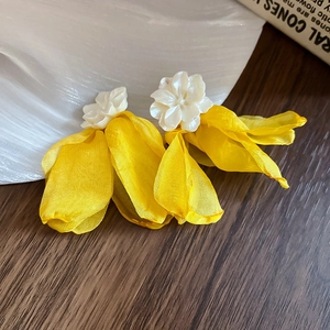 Detailed shot of yellow silk petal tassel earrings with a white floral resin stud base