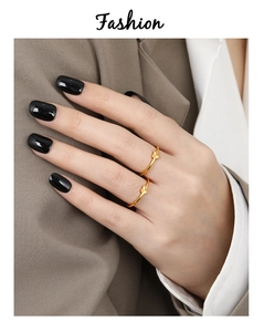 Detail of two gold-plated thin rings with heart-shaped charms worn on a hand