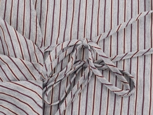 Detailed close-up of gray striped fabric with burgundy vertical lines and bow tie waist detail