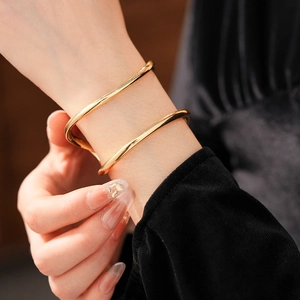 Gros plan d'un bracelet manchette doré ondulé à double couche sur le poignet